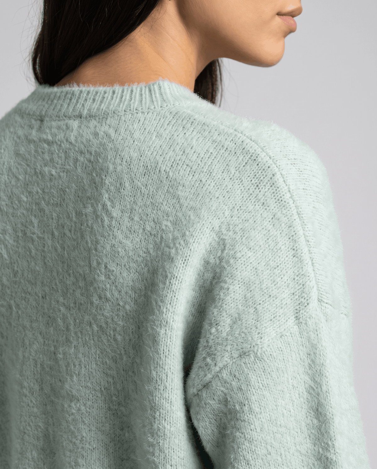 Detail of the green plush knit along the dropped shoulder seam