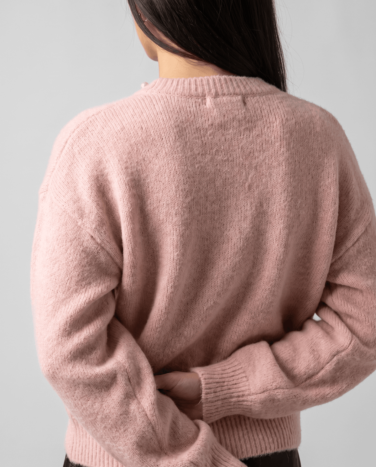 Back view of the pink cardigan showing its relaxed shape and ribbed hem