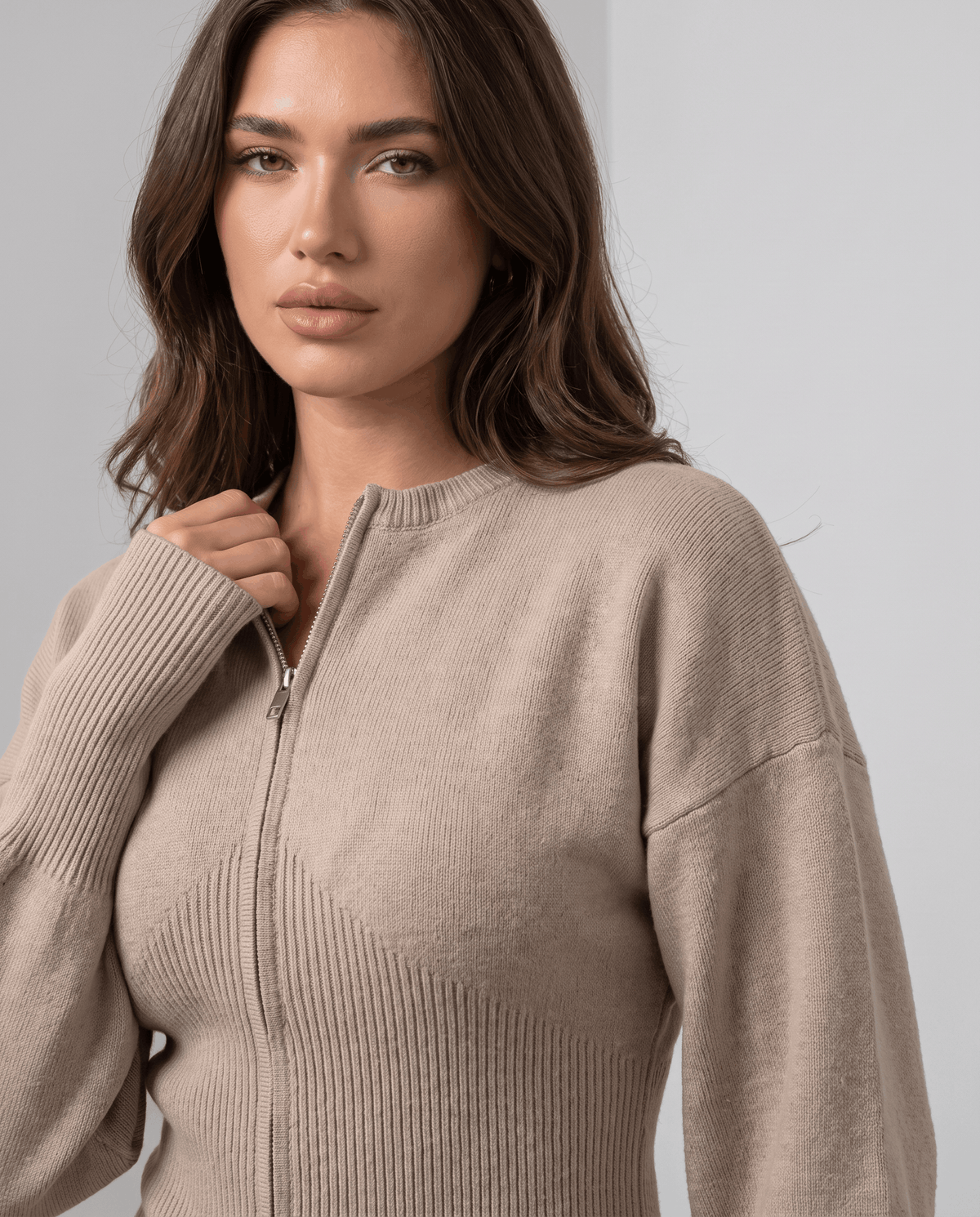 Close-up of the front zip and ribbed waist on the beige knit top