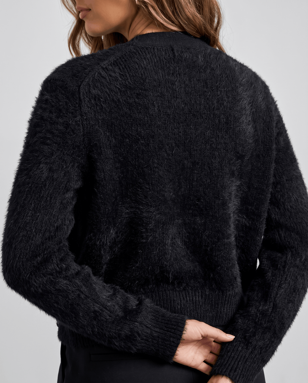 Back view of the black cardigan with its cropped length and ribbed cuffs