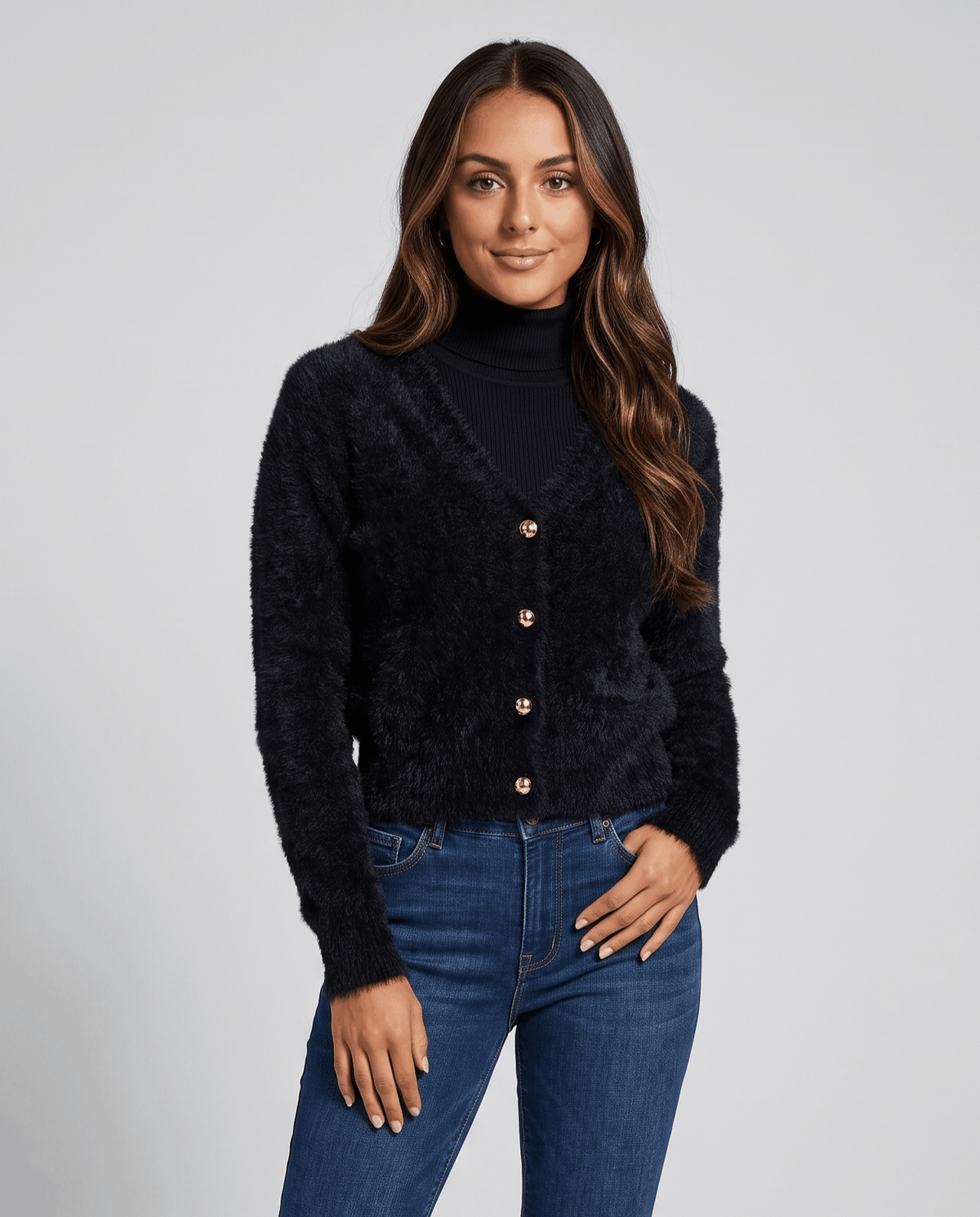 Black cardigan buttoned over a black turtleneck with blue jeans