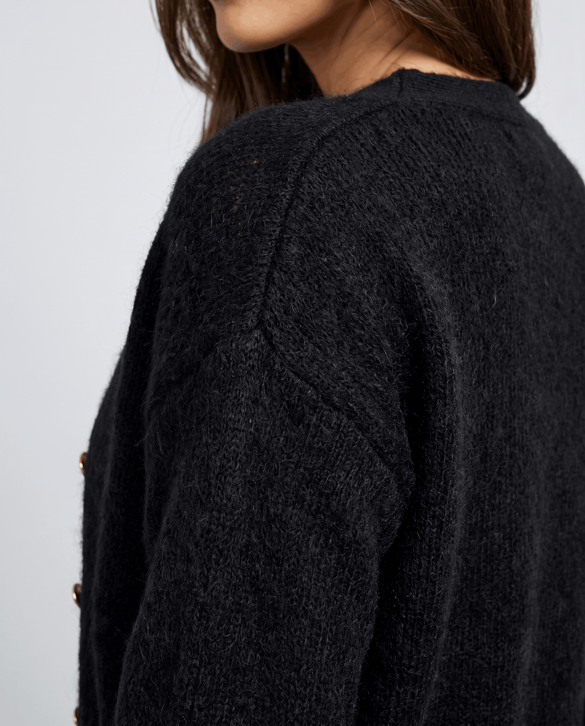 Side view of the black fuzzy knit along the shoulder and sleeve