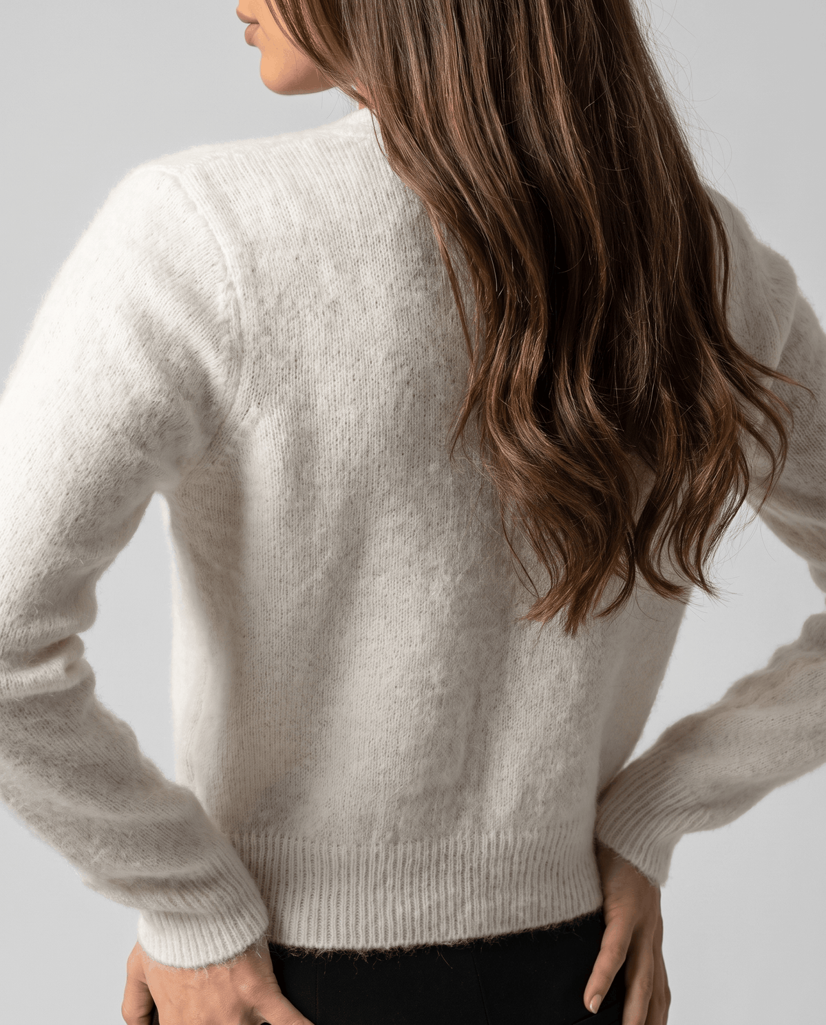 Back view of the white cardigan showing the fuzzy knit and ribbed hem