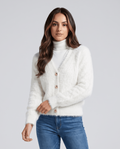 Women's cropped V-neck cardigan in white over a turtleneck with blue jeans
