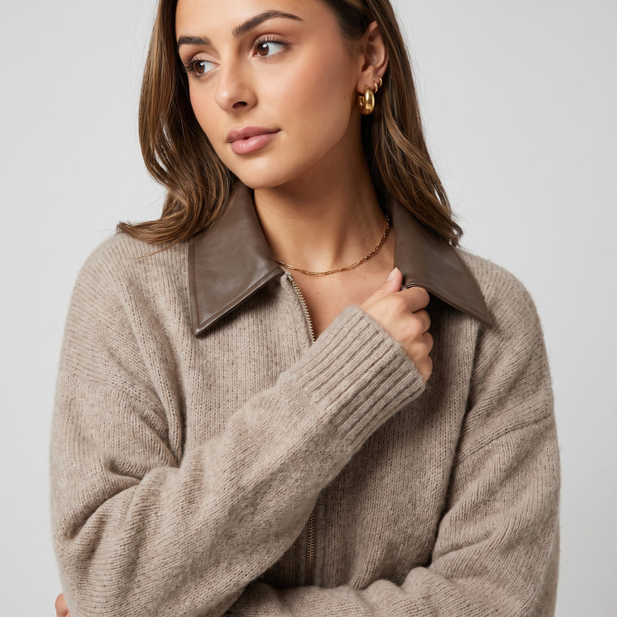 Detail of the leather-look spread collar and ribbed cuff with a gold necklace