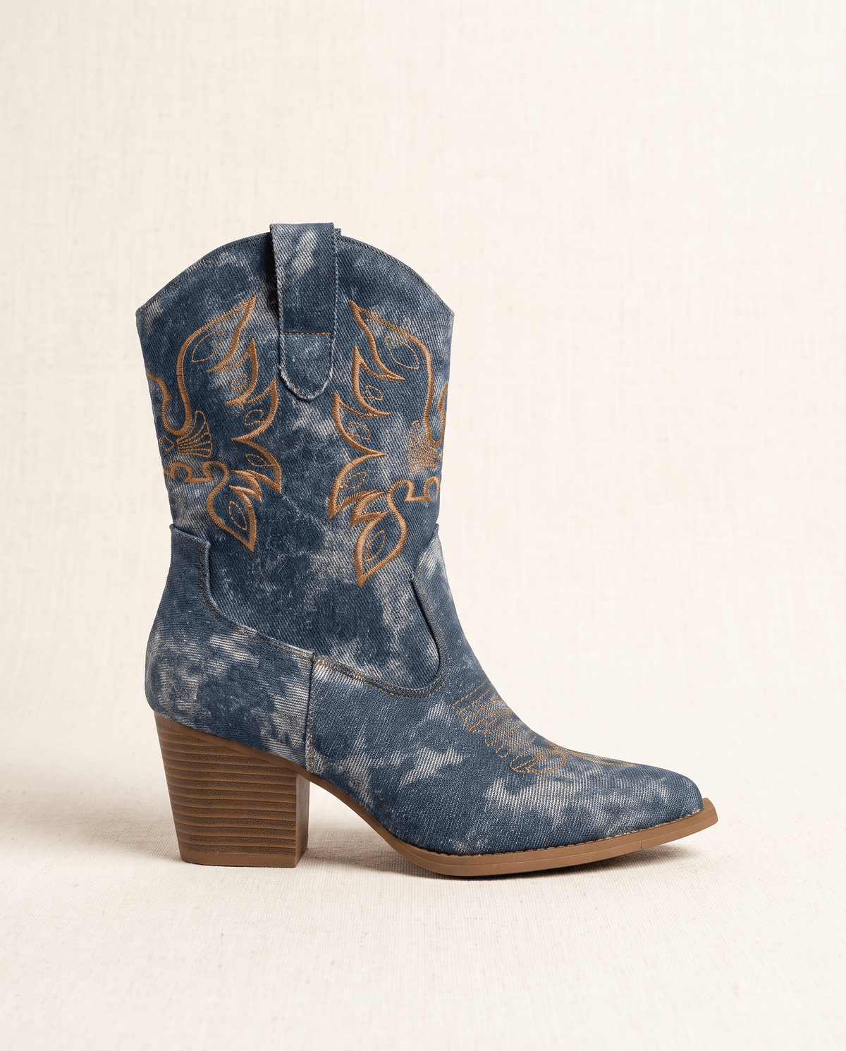 Side view of a single blue washed denim-look boot with brown block heel and embroidery