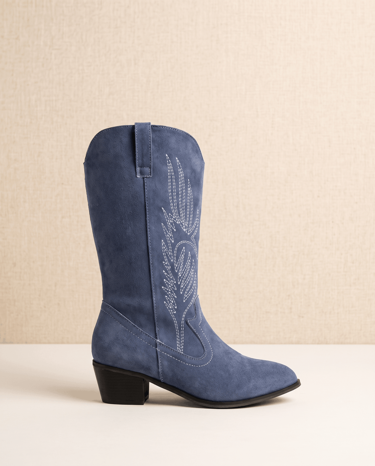 Side view of a single mid-calf navy suede boot with embroidered shaft and black block heel