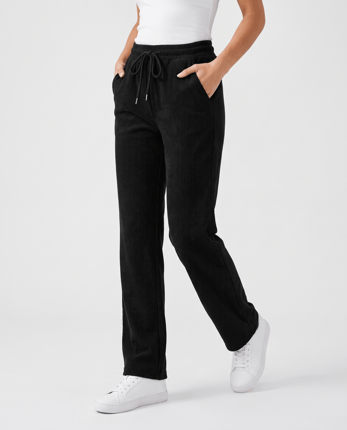 Woman wearing black fleece-lined corduroy wide-leg pants with a drawstring waist and white sneakers
