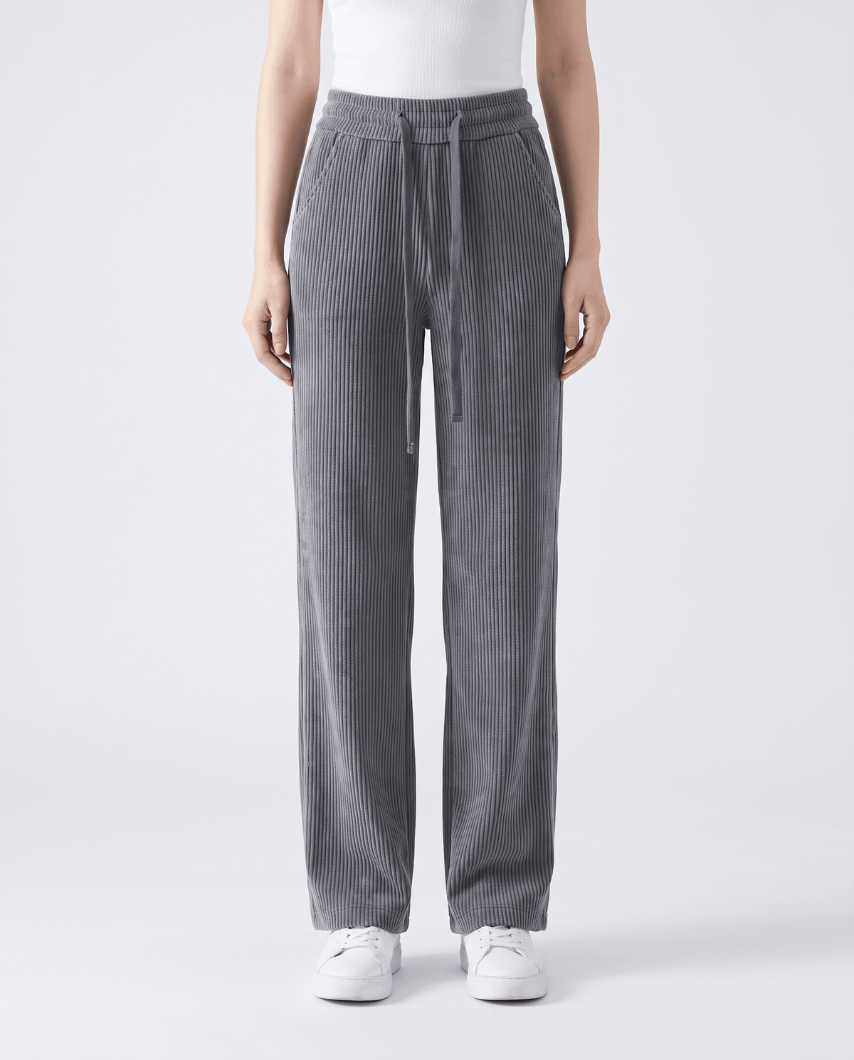 Front view of gray wide-leg corduroy pants with a drawstring waist and white sneakers