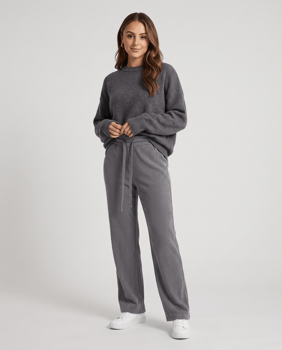 Model in gray ribbed pants styled with a matching gray sweatshirt and white sneakers