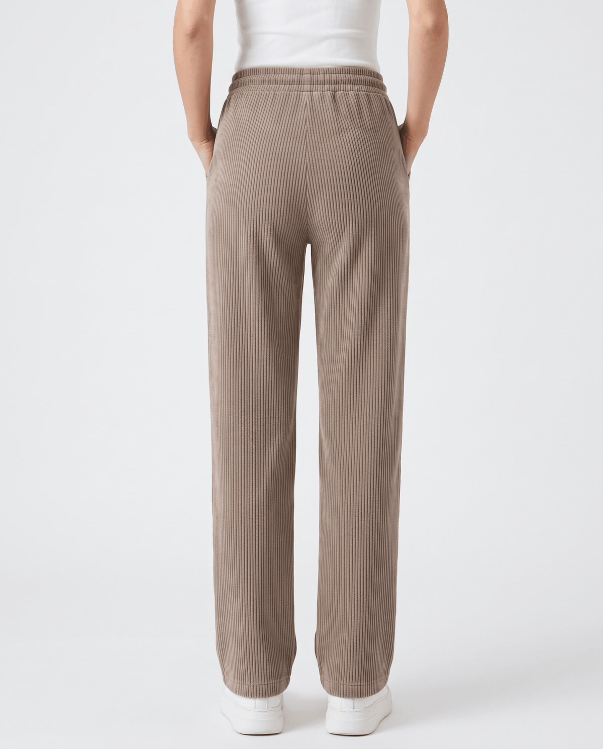 Back view of mocha ribbed wide-leg trousers with an elastic waist and white sneakers