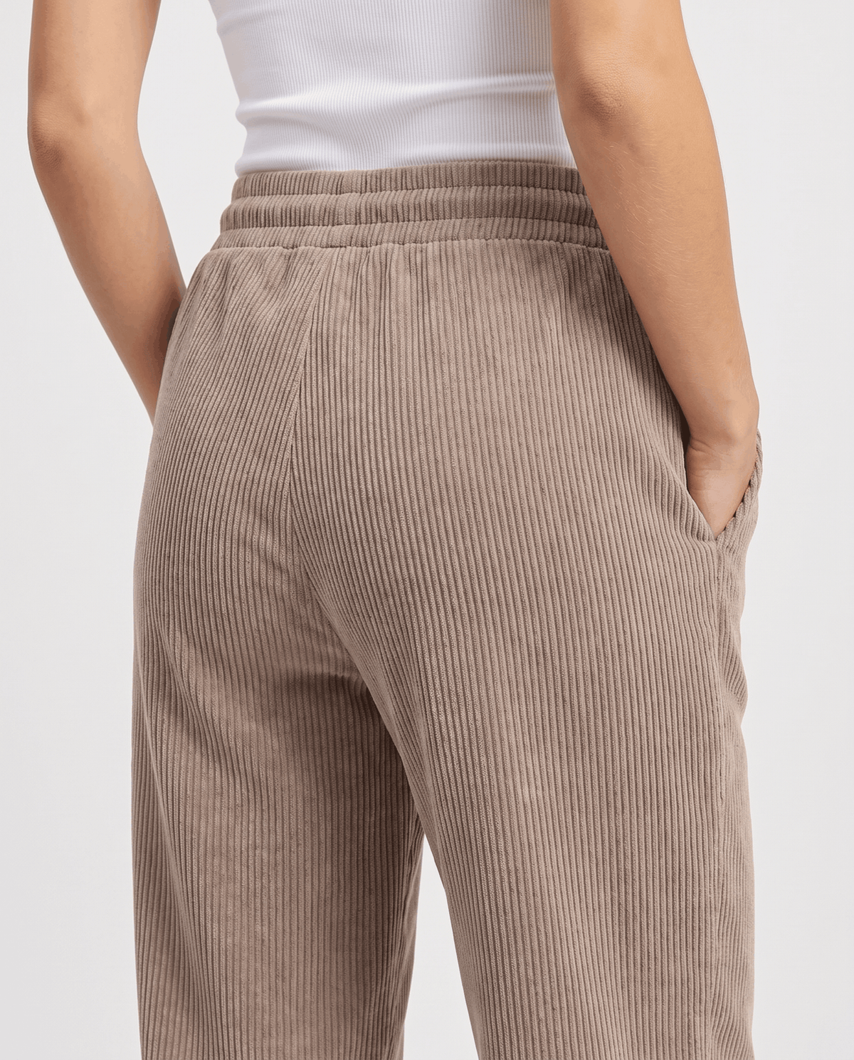 Back close-up of taupe wide-rib corduroy showing the elastic waistband and hip fit