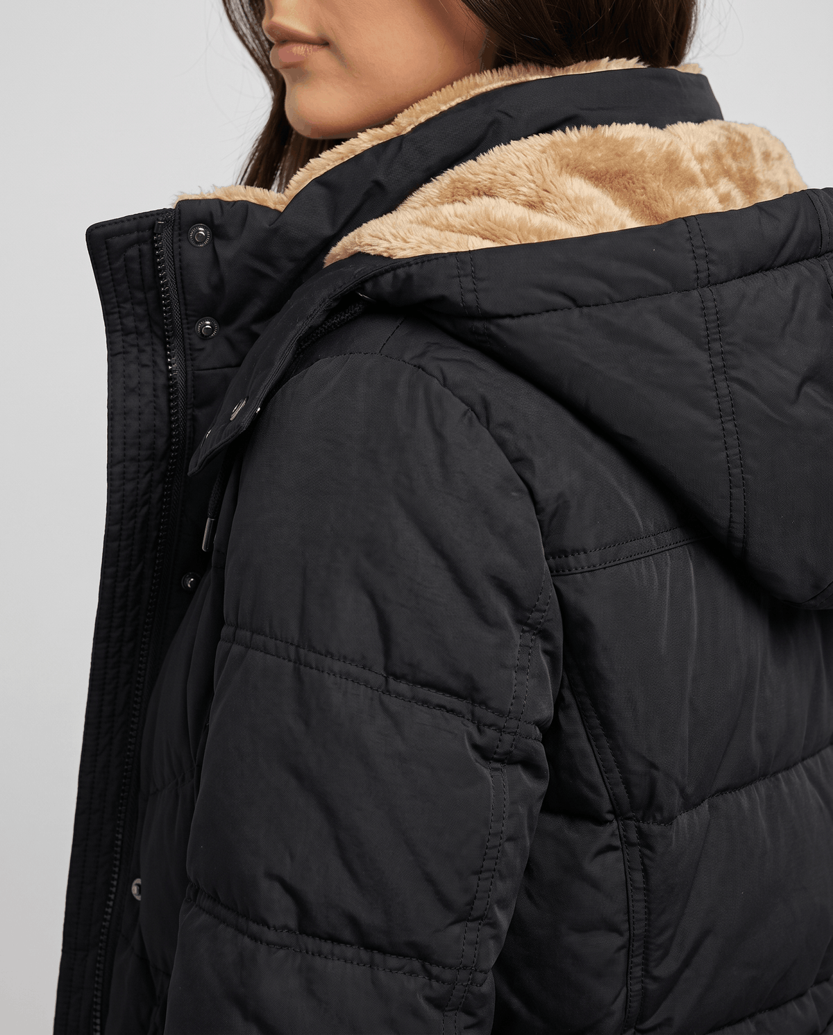 Side close-up of the fleece hood lining on a black quilted coat