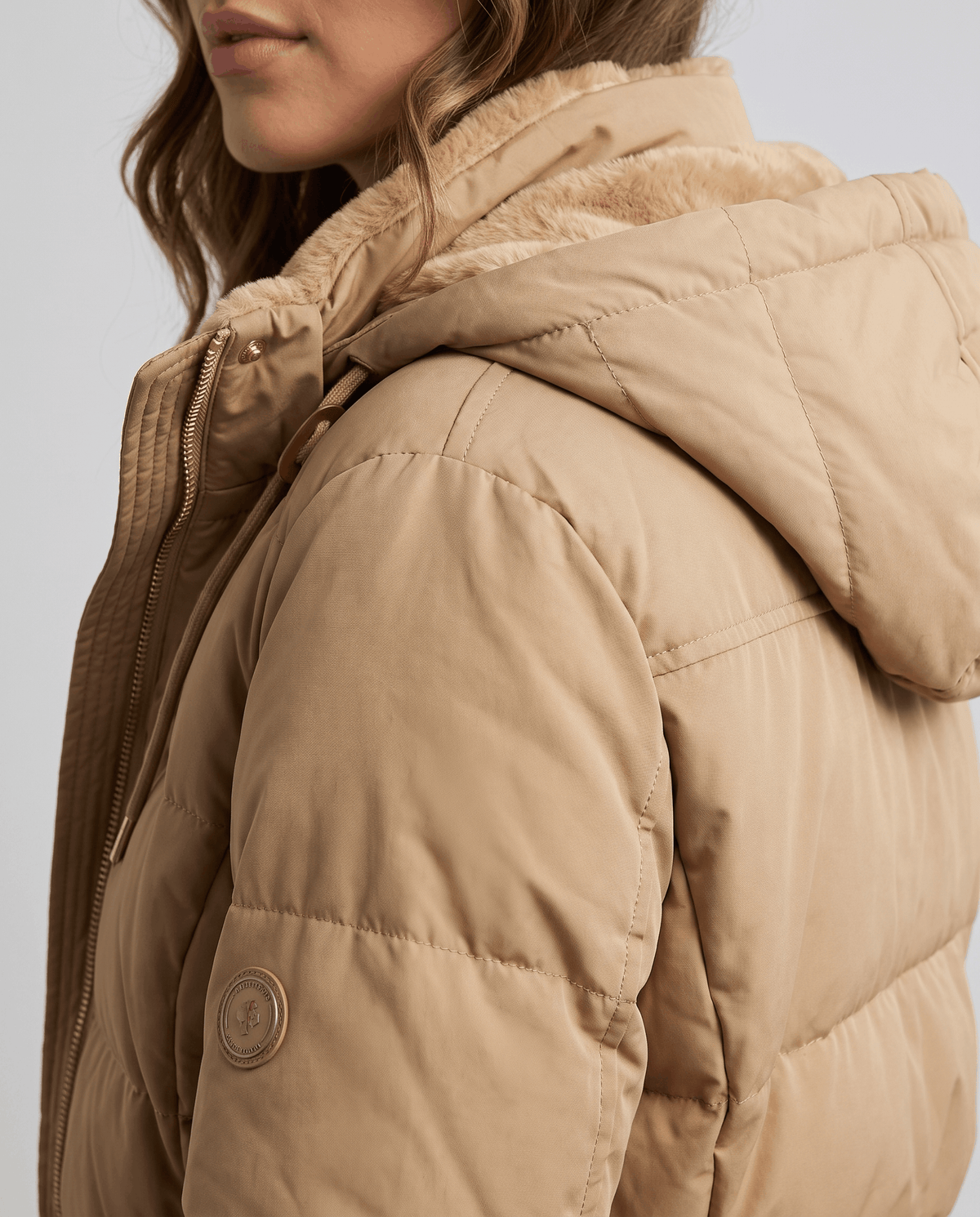 Side close-up of fleece hood lining on a camel quilted parka