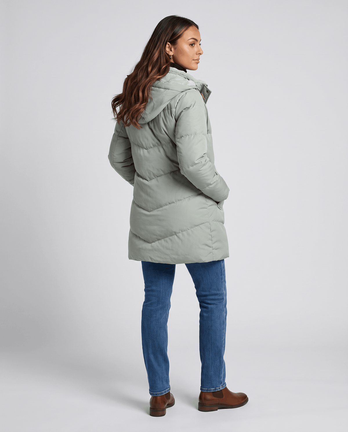 Back view of sage green parka with hood down over blue jeans