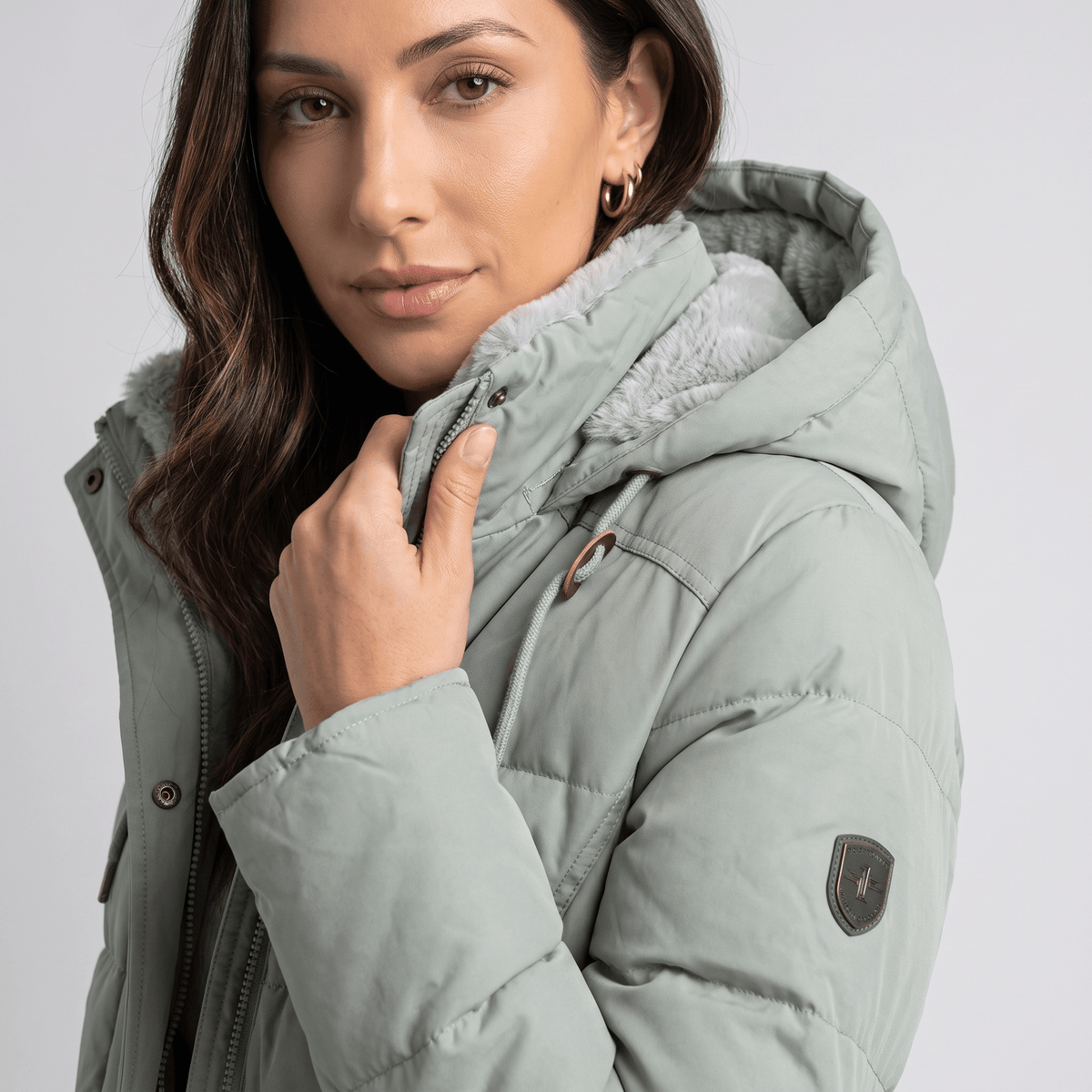 Close-up of sage green parka collar, snap placket and sleeve patch