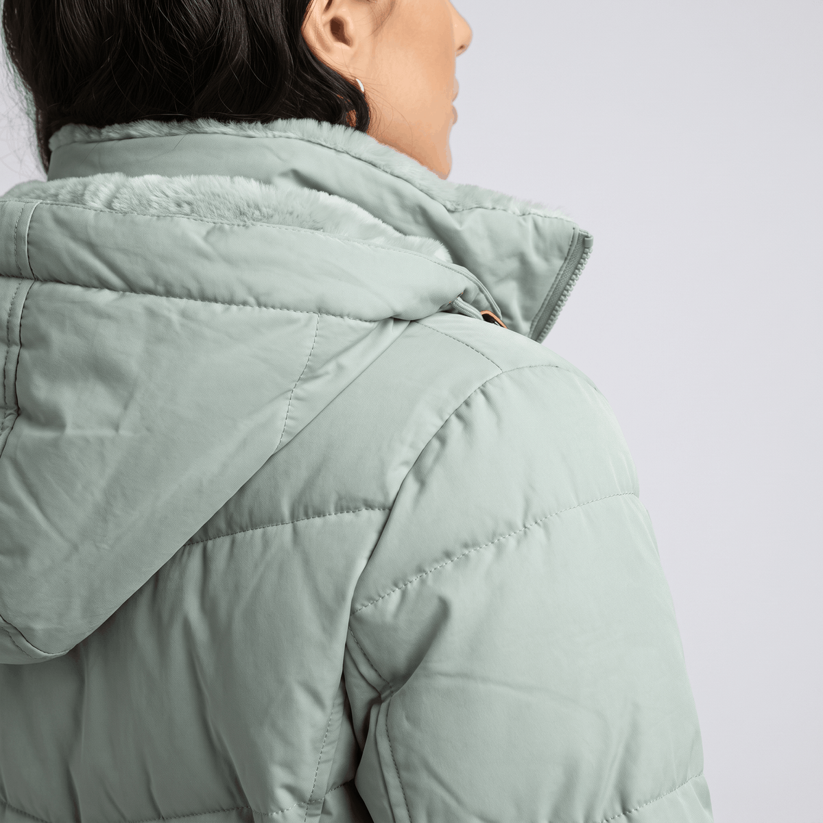 Rear shoulder detail showing the hood and chevron quilting in sage green