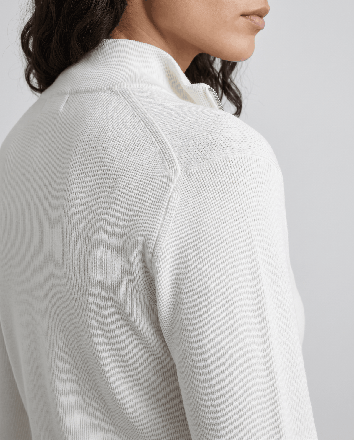 Close-up of the knit texture at the shoulder of the beige zip jacket