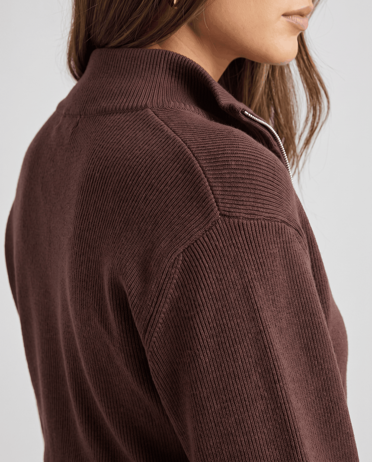 Close-up of the stand collar and shoulder seam on the dark brown knit zip jacket