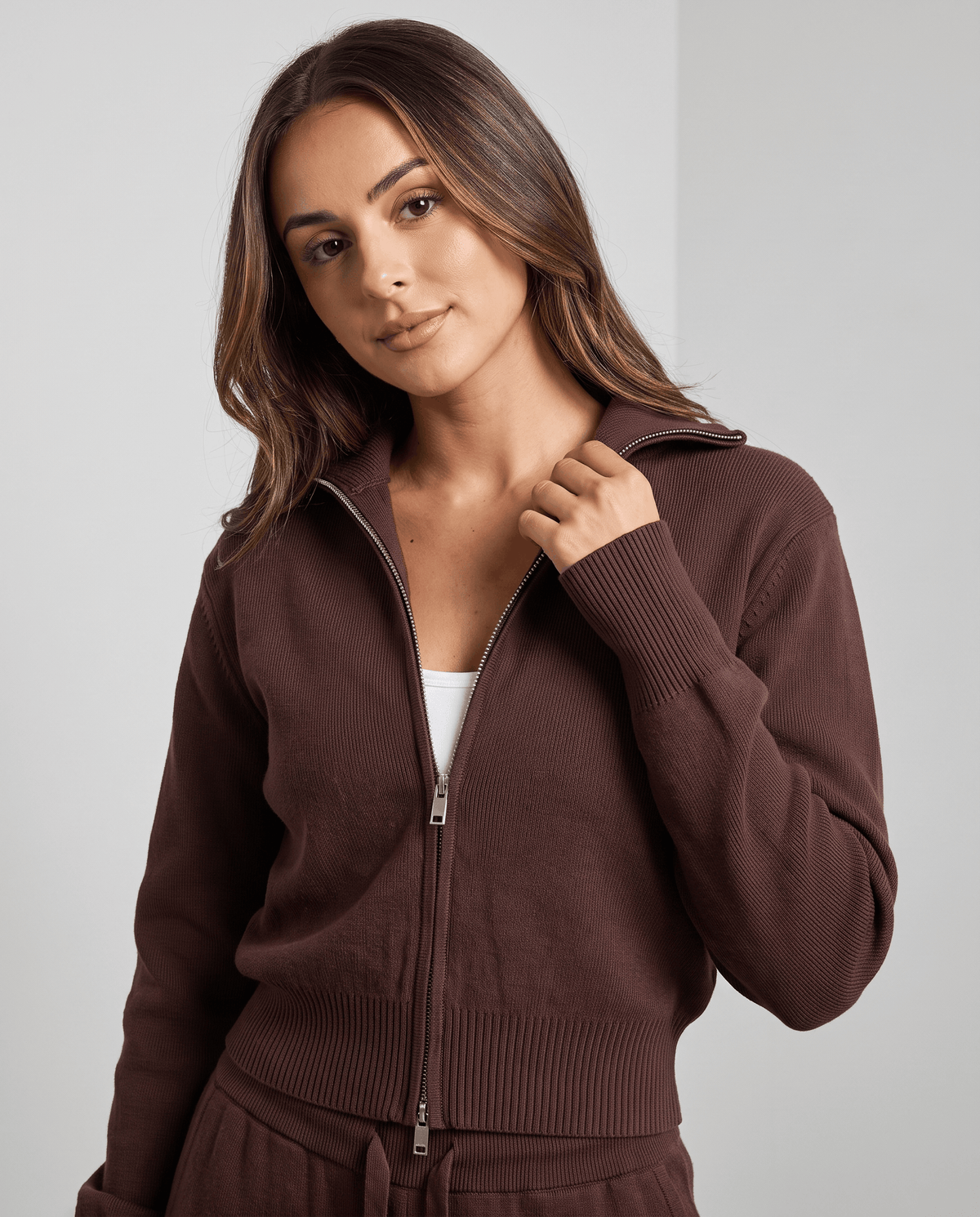 Close-up of the full zip, folded collar and ribbed hem on the dark brown knit jacket
