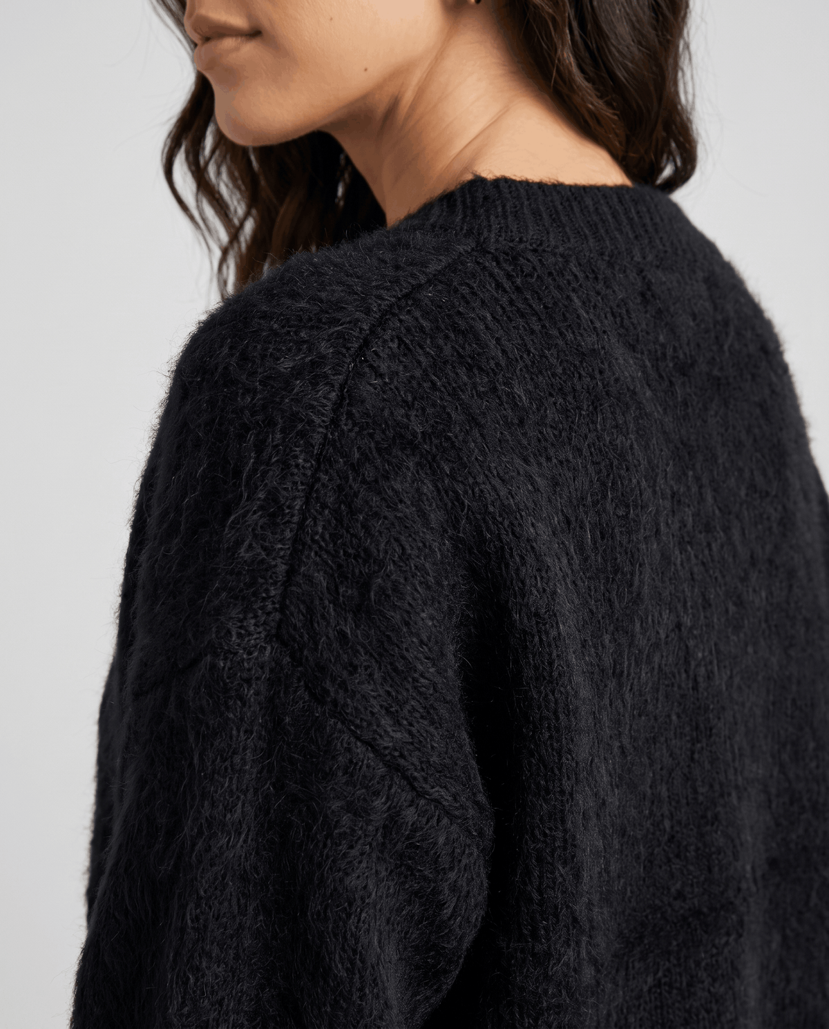 Detail of the black fuzzy knit along the raglan shoulder seam