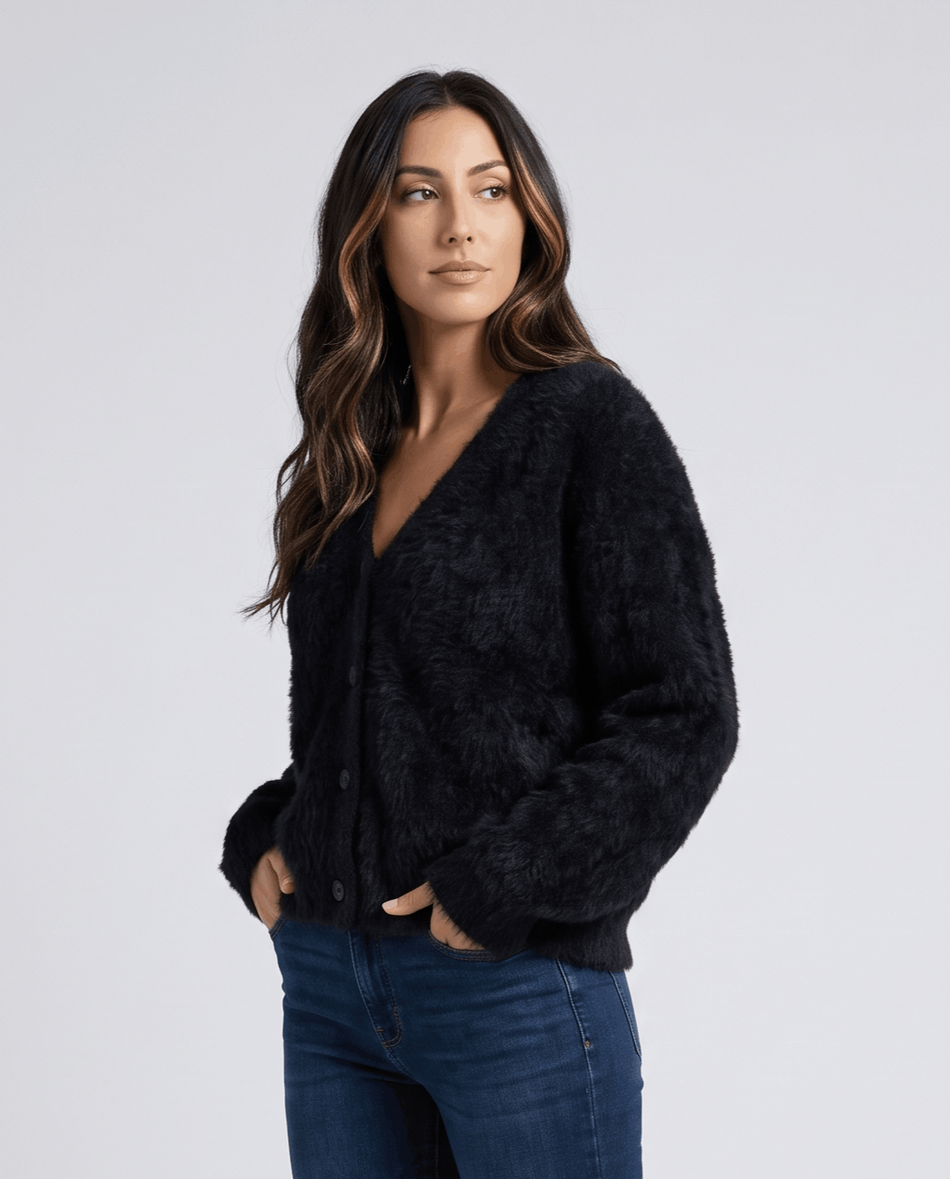 Black cardigan in a side pose with hands in jean pockets