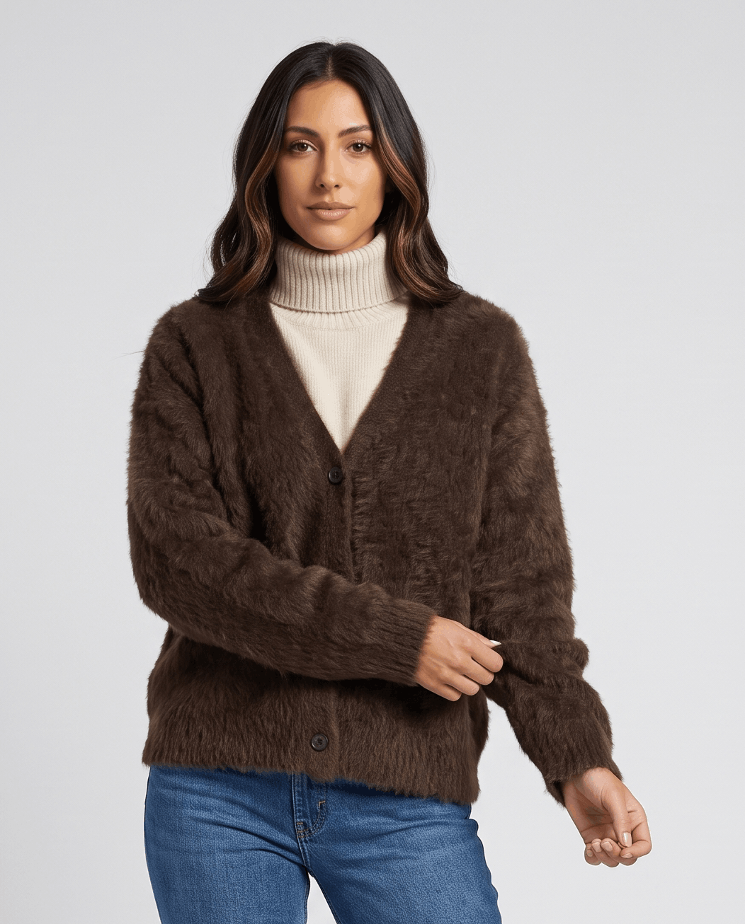 Brown cardigan over a cream turtleneck with blue jeans