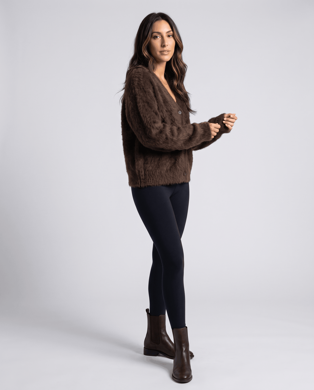 Side view of the brown cardigan with black leggings and ankle boots