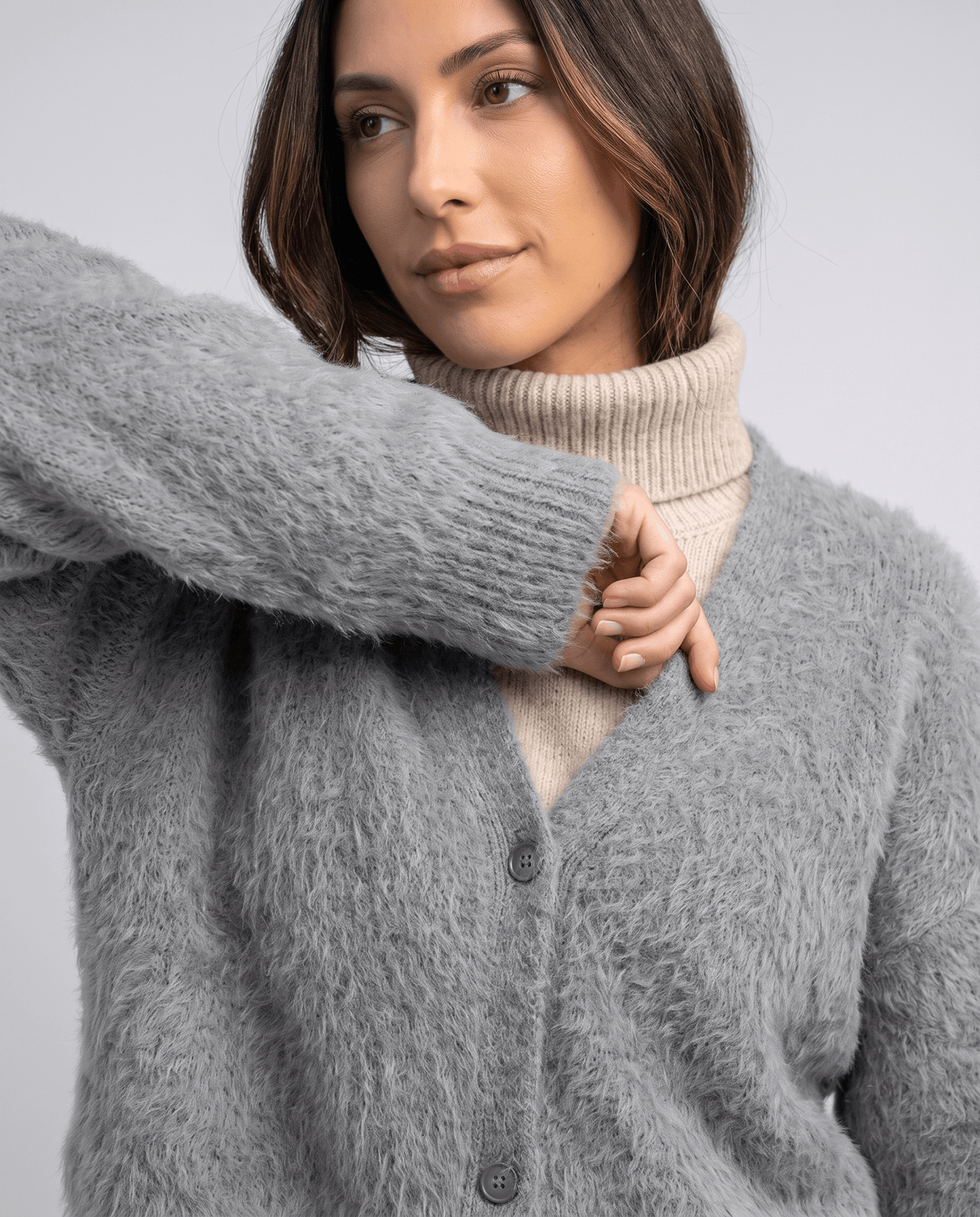 Light gray cardigan close-up with a hand at the ribbed cuff