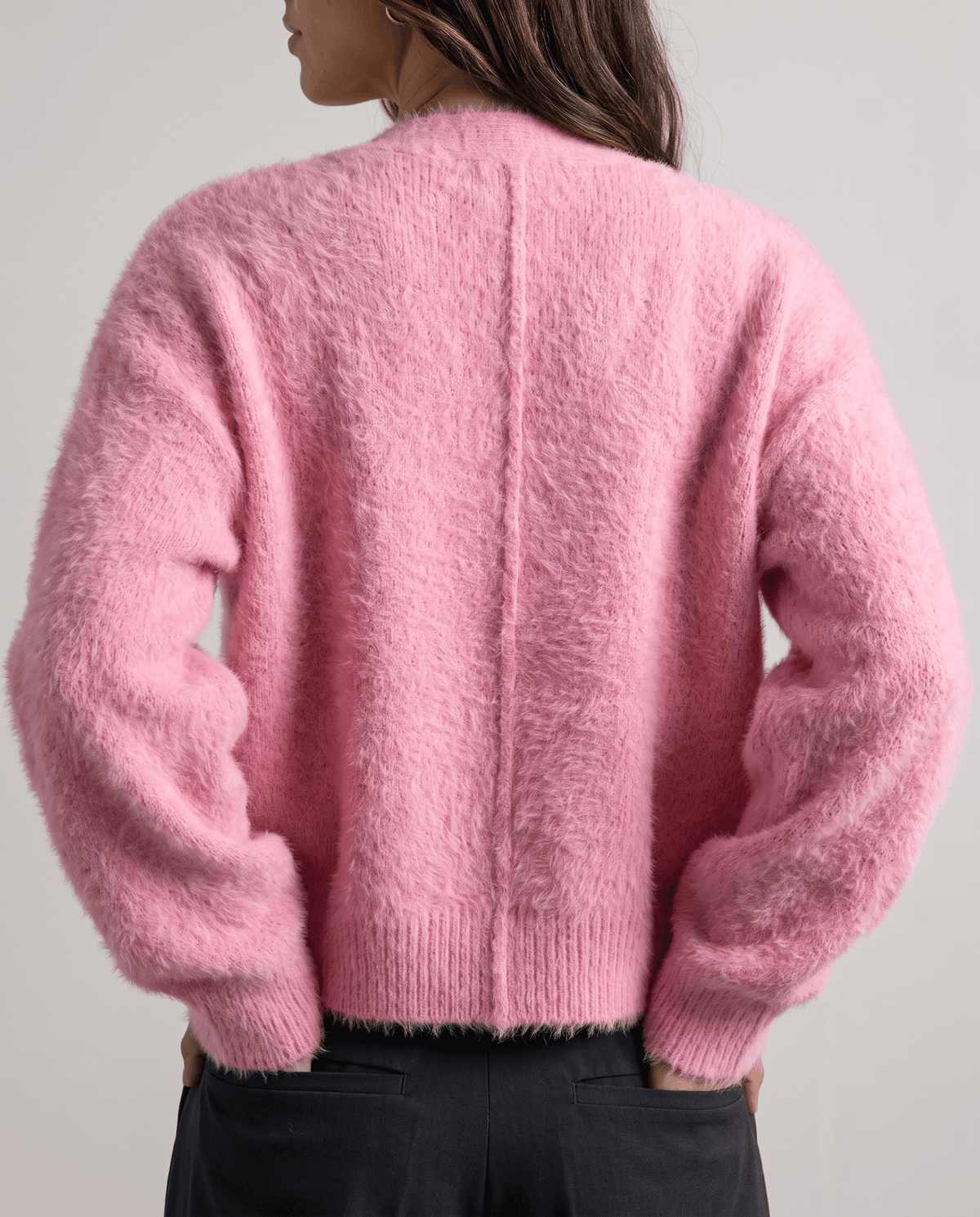 Back view of the pink cardigan with its oversized shape and ribbed hem