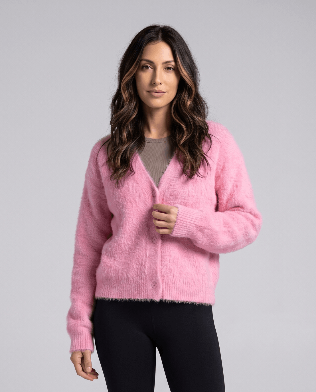 Pink cardigan buttoned over a taupe top with black pants