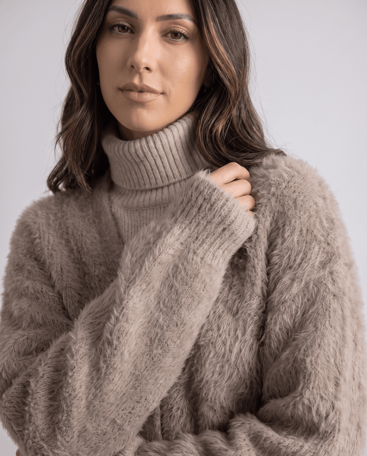 Taupe cardigan close-up with a hand resting at the collar