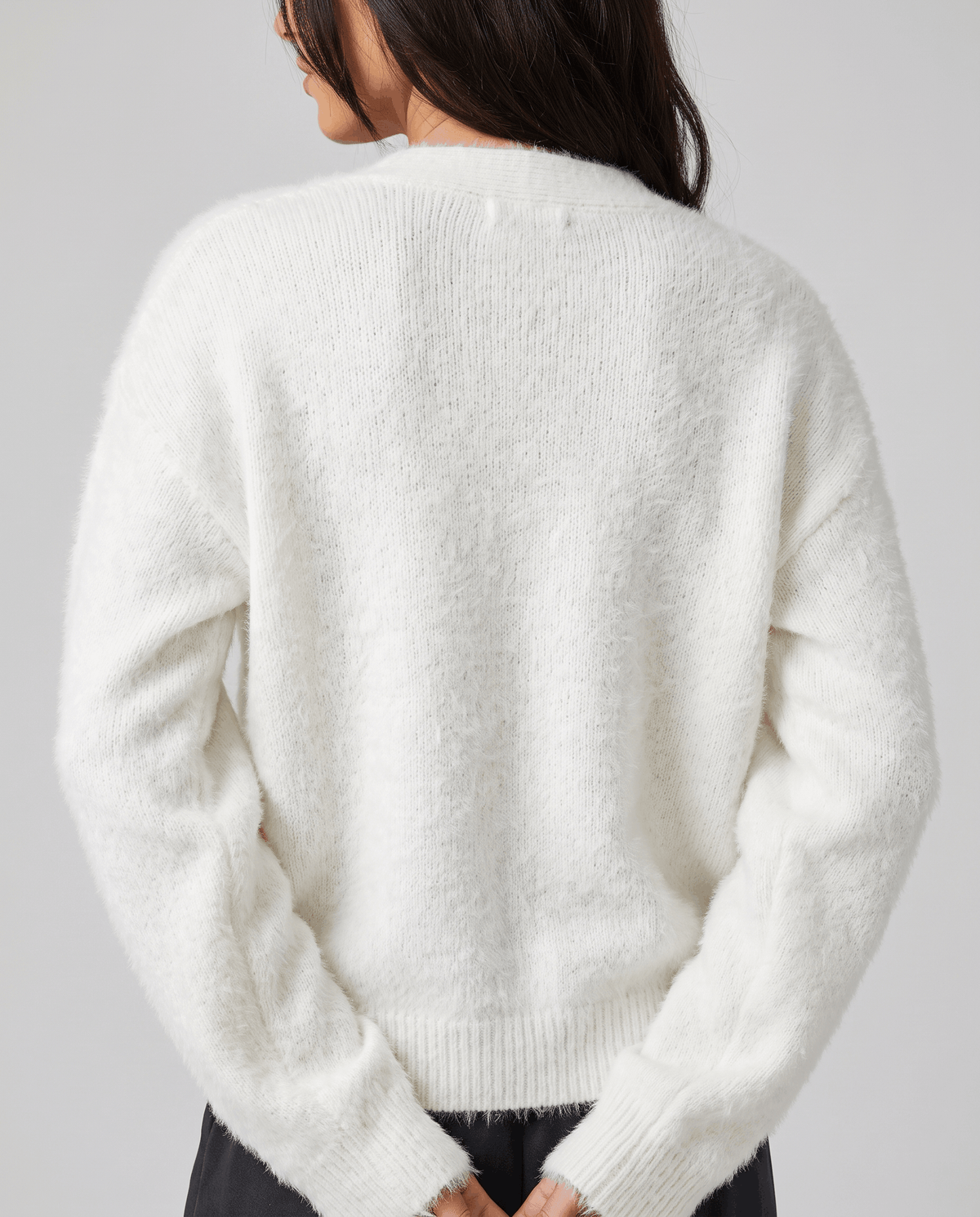 Back view of the white fuzzy knit showing the ribbed hem