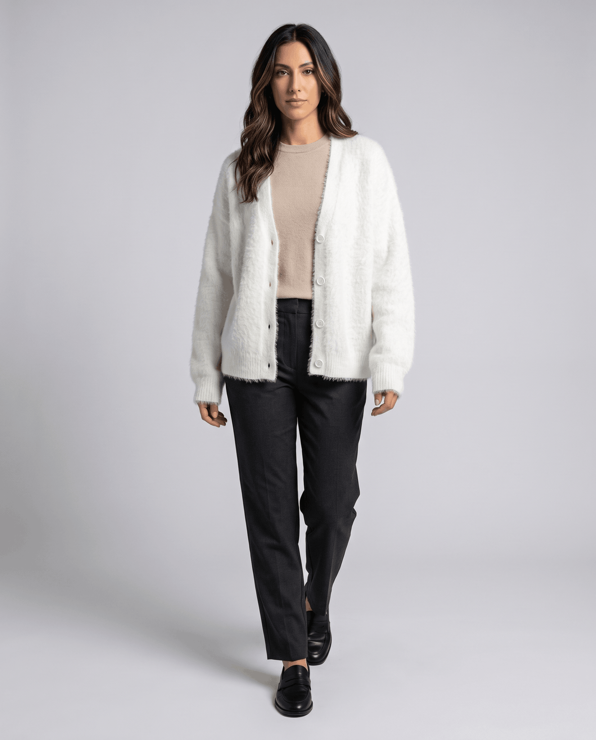 Full-length white cardigan outfit over a beige top and dark trousers