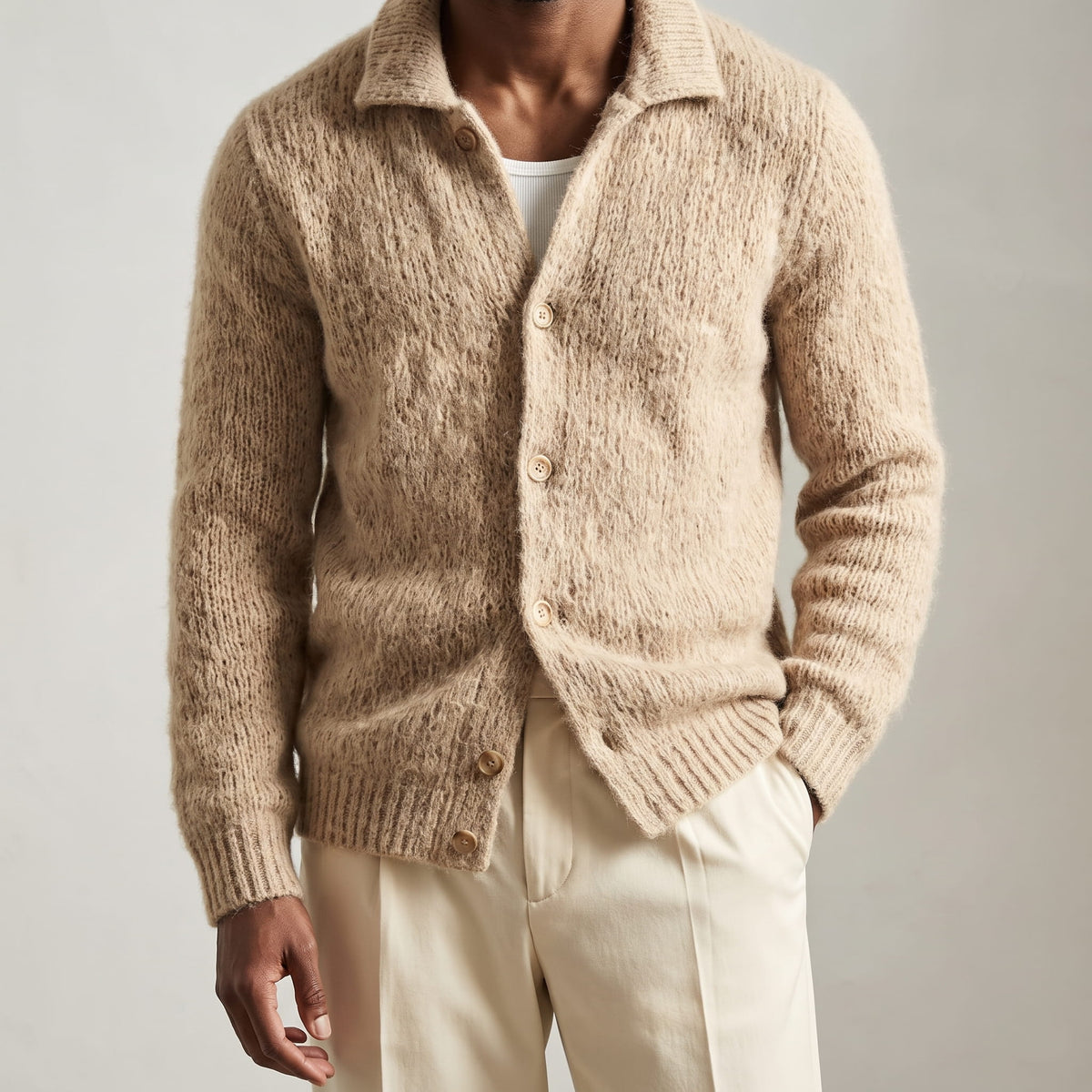 Front view of the buttoned khaki cardigan with hands in trouser pockets