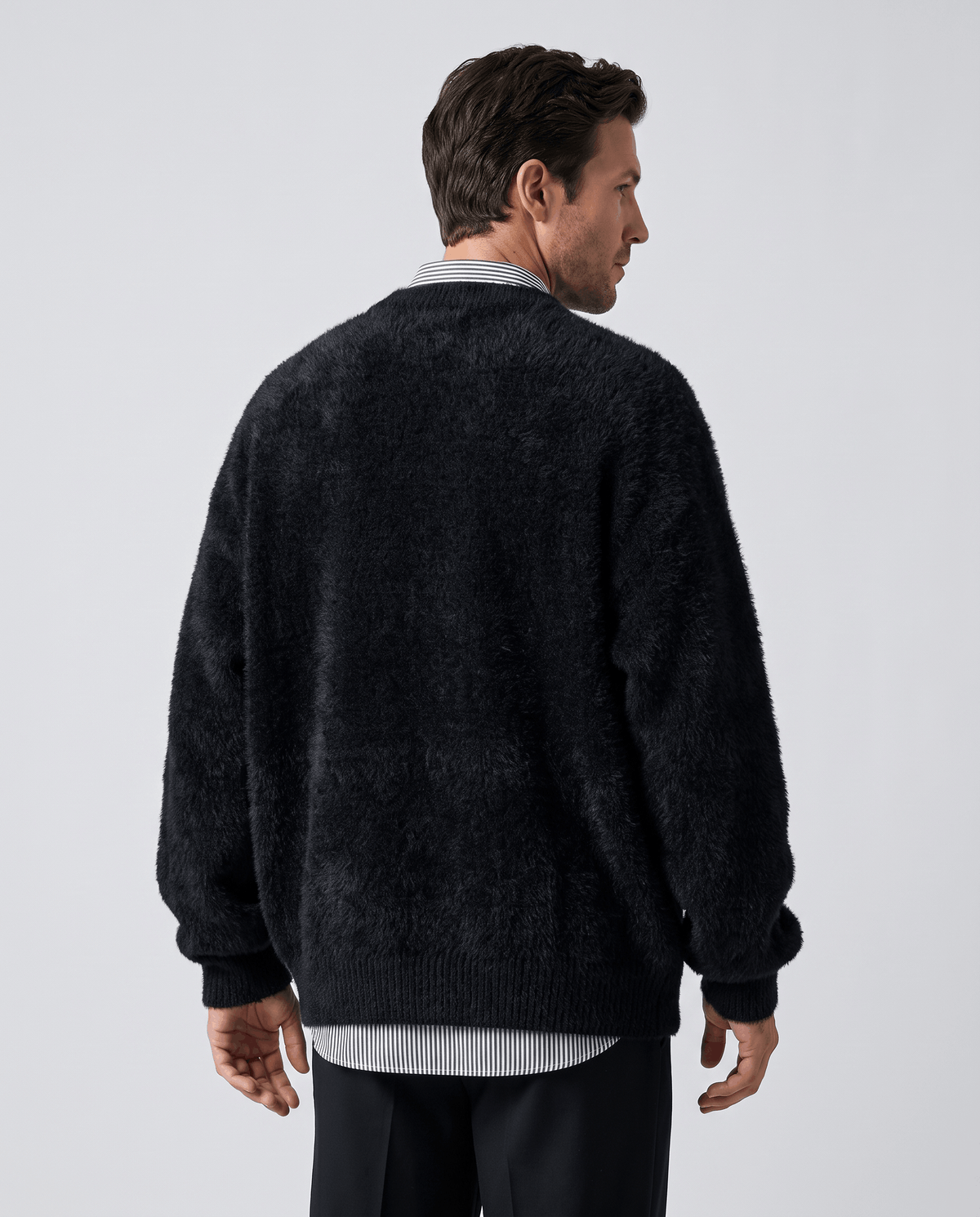 Back view of the black oversized sweater with a shirt hem showing beneath