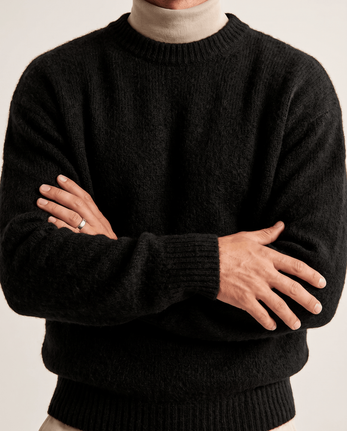 Front close-up of the black sweater over a beige turtleneck with arms crossed