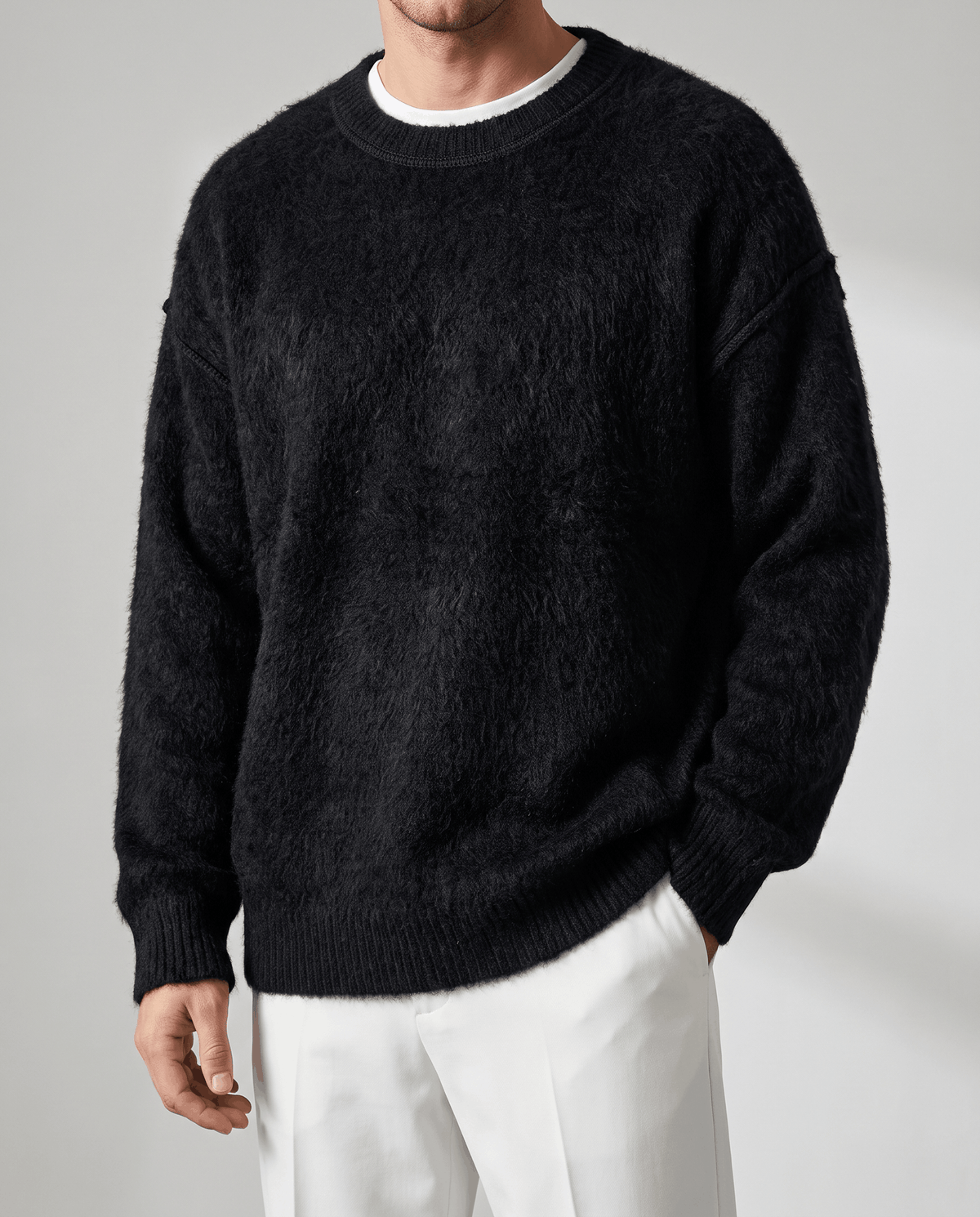 Front view of the oversized black pullover worn over a white tee with white trousers
