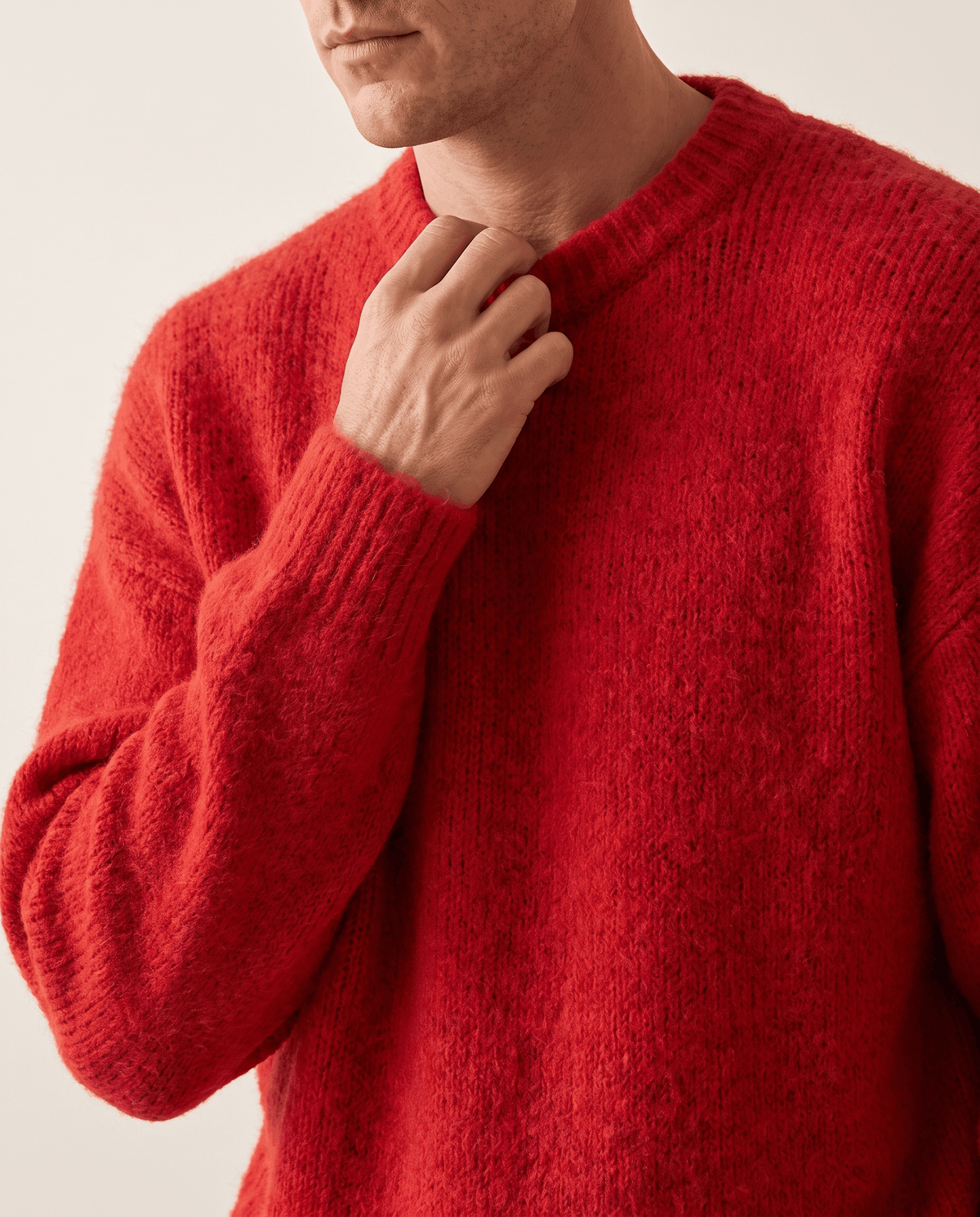 Close-up of a hand at the ribbed collar of the red brushed knit pullover