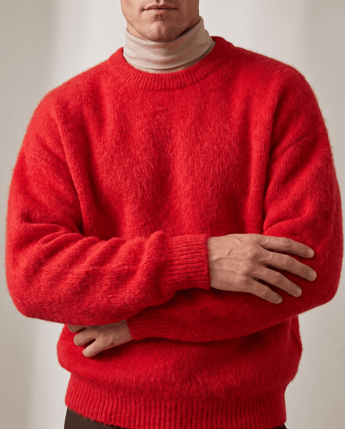 Front close-up of the red sweater over a beige turtleneck with arms crossed