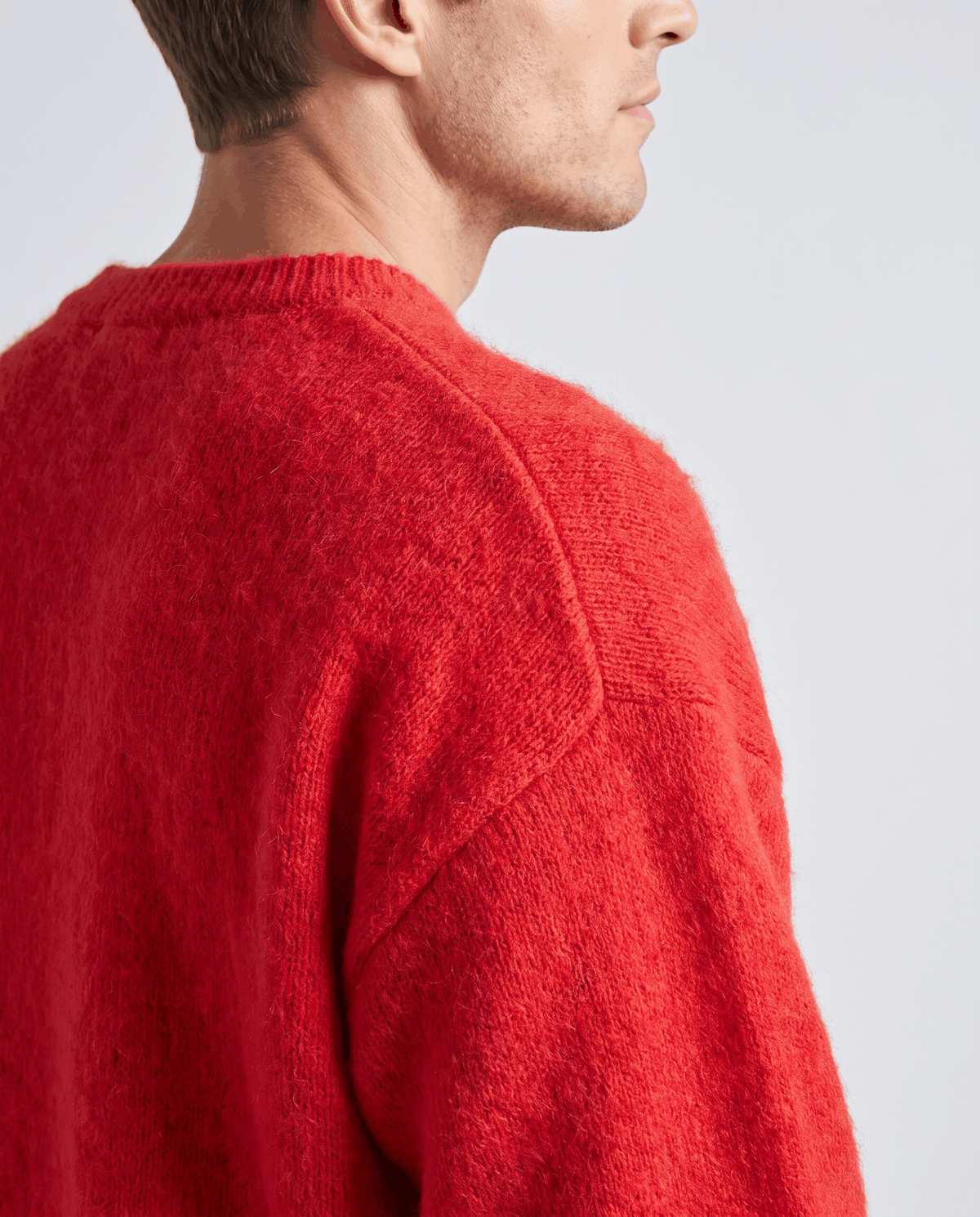 Shoulder detail of the red sweater showing the hazy knit and dropped seam