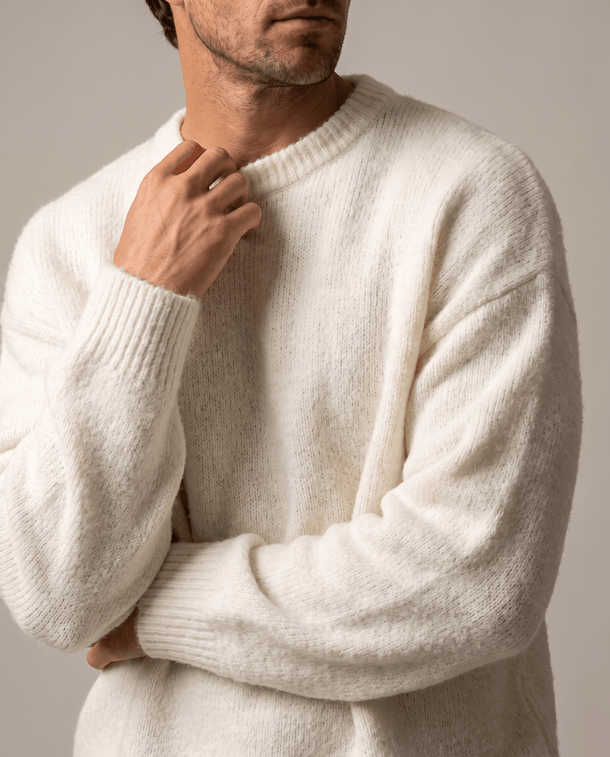 Close-up of a hand at the ribbed crew neck of the white brushed knit sweater