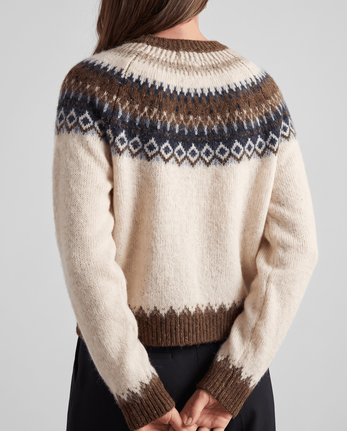 Back view of the beige cardigan showing the patterned yoke and ribbed hem