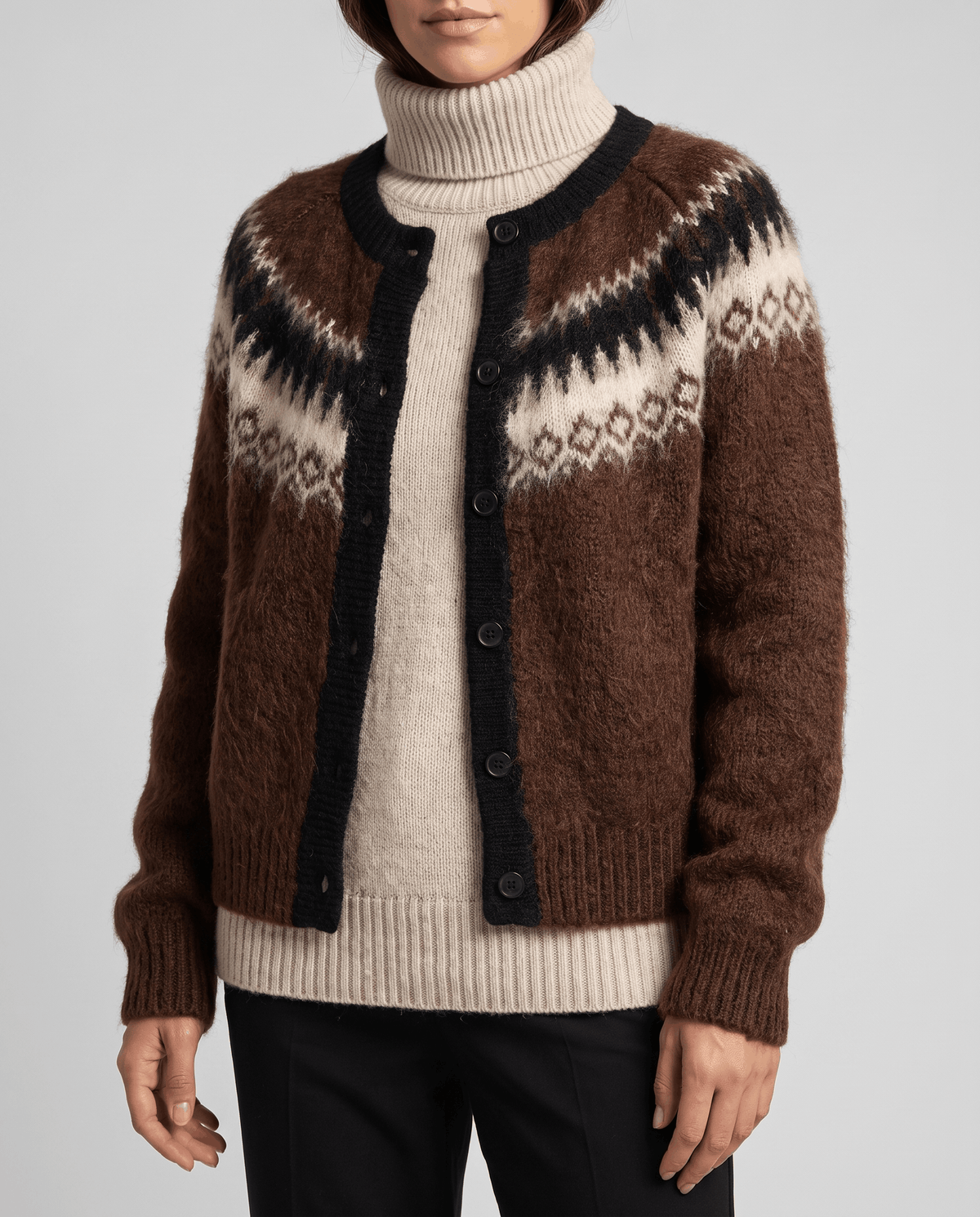 Brown cardigan worn open over a cream turtleneck sweater and dark pants