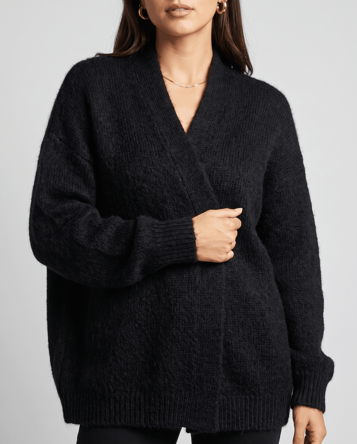Close-up of the black cardigan wrapped closed at the front by hand