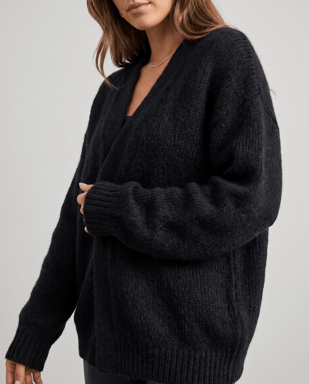 Three-quarter view of the black cardigan highlighting the roomy sleeves and ribbed hem