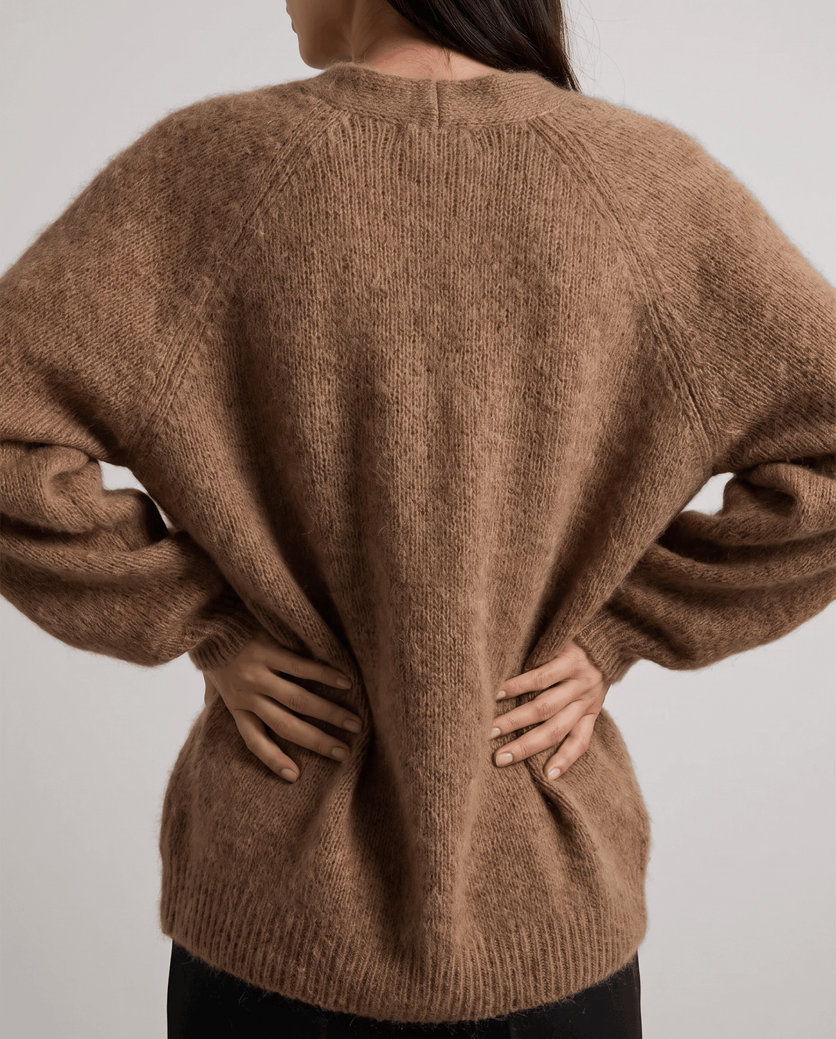 Brown cardigan from behind with hands on hips showing its relaxed wide cut