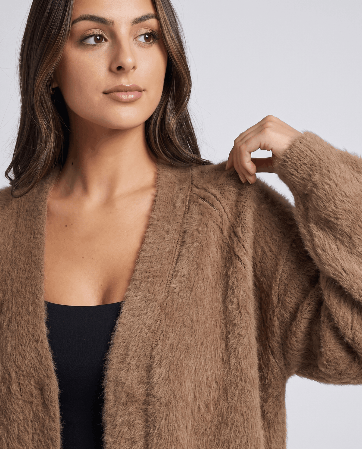 Close-up of the brown cardigan pulled open over a black scoop-neck top