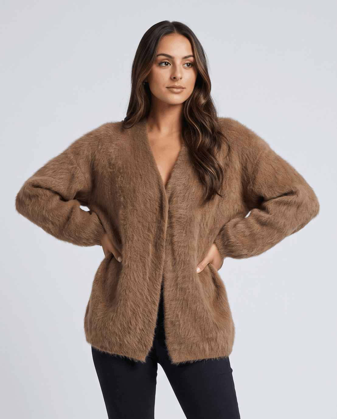 Brown cardigan worn over a black top with hands resting on the hips