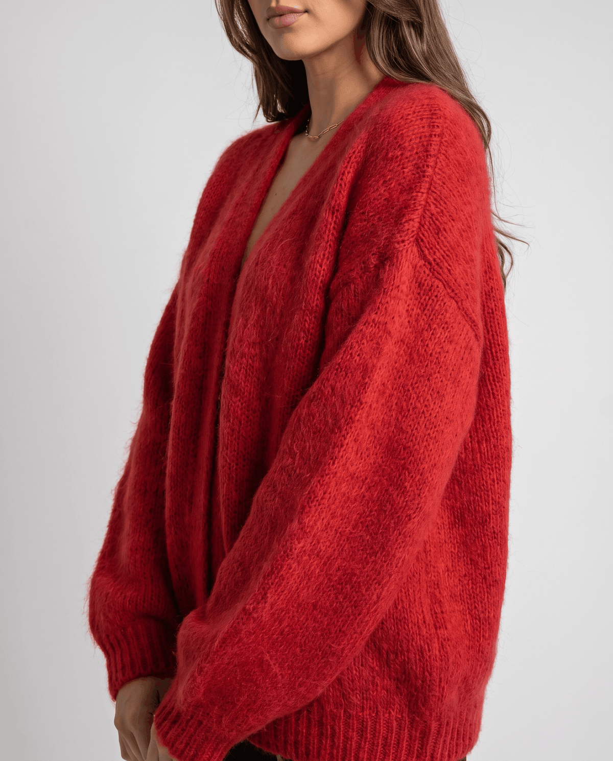 Side view of the red cardigan showing its full sleeve and ribbed cuff